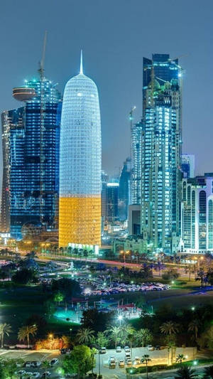 夜晚的城市景觀，有燈火通明的摩天大樓和棕櫚樹。 — 城市 壁紙