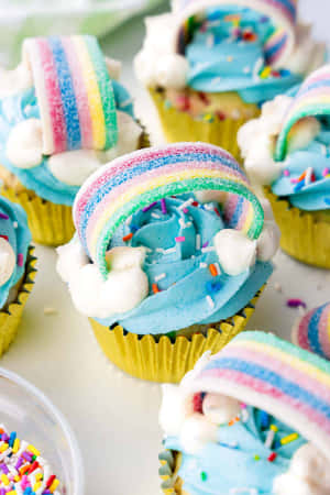 彩虹主題杯子蛋糕，配藍色糖霜和彩色糖粒。 — 2:3 壁紙