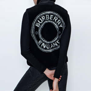 一個人穿著帶有白色標誌的黑色Burberry背心，站在白色牆壁前。 — Burberry 壁紙
