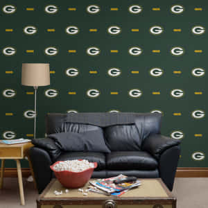 黑色皮革沙發前有 Green Bay Packers 壁紙，咖啡桌上有爆米花和雜誌。 — 綠灣包裝工 壁紙