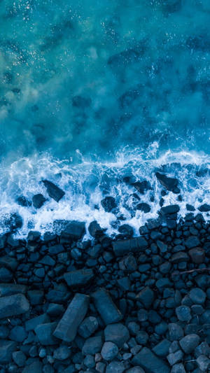 碧綠色的海浪拍打深色岩石，激起白色泡沫。 — 波浪 壁紙