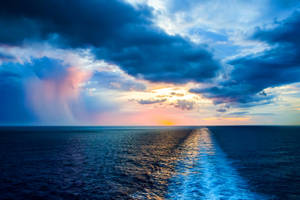 在戲劇性的夕陽和多彩雲彩中，船隻的尾跡穿過海洋。 — 海洋桌面 壁紙