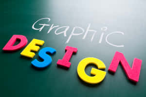 多彩的泡沫字母拼出DESIGN在綠色黑板上，並用粉筆寫著'Graphic'。 — MacBook Pro 16 壁紙