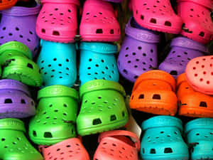 一堆色彩繽紛的Crocs木屐，呈現明亮的霓虹色調。 — Crocs 壁紙