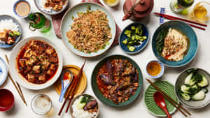 色彩繽紛的亞洲菜餚，包括麵條、豆腐和茄子，盛在陶瓷碗中，附有筷子和飲料。 — 高對比 壁紙