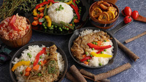 深色表面上的加勒比餐點，有米飯、豌豆、雞肉和大蕉。 — 4K 食物 壁紙