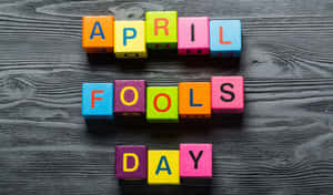 色彩繽紛的積木在深色木頭上拼出April Fools Day。 — 海灘 壁紙
