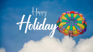 「Happy Holiday」文字與彩色降落傘在雲層上空飛翔。 — 節日 GIF 壁紙