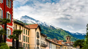 色彩繽紛的城鎮建築，背景是白雪覆蓋的山脈 — 瑞士 壁紙