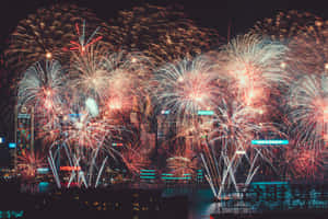 五顏六色的煙火照亮了水面上夜晚的城市景觀。 — 慶祝 壁紙