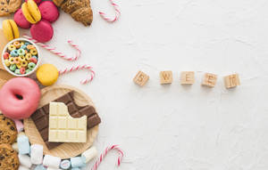 甜甜圈、馬卡龍和巧克力等甜點與拼出sweet的木塊一起排列。 — 烘焙坊 壁紙