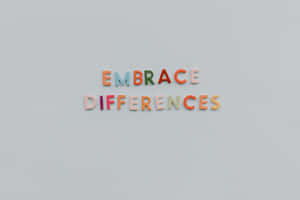 色彩繽紛的磁鐵字母在灰色牆上拼出 embrace differences。 — MacBook Air 15 壁紙