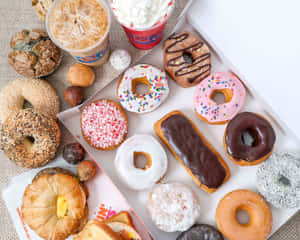 一盒綜合甜甜圈、貝果和糕點，搭配冰咖啡和鮮奶油。 — Dunkin Donuts 壁紙