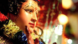 裝飾有花環和背後發光燈光的宗教雕像特寫。 — Maa Durga 壁紙