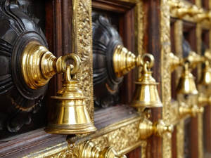 金色鈴鐺掛在雕花木門上，帶有鍍金細節。 — 金廟 壁紙