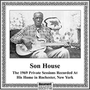 Son House 手持共鳴吉他的裱框照片，下方有專輯文字。 — 音樂 壁紙