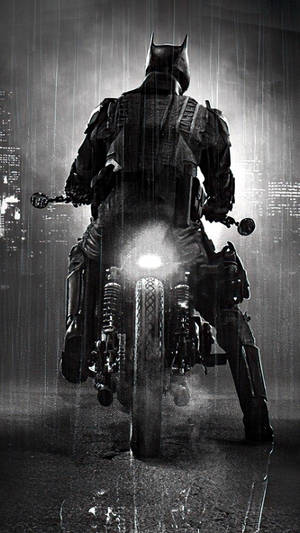 蝙蝠俠在雨中騎摩托車，身後有城市燈光。 — 蝙蝠車 壁紙