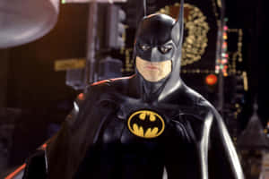 蝙蝠俠穿著帶有黃色標誌的黑色西裝，站在夜晚的城市場景中。 — MacBook Air M4 壁紙