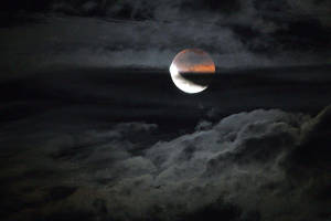 血月部分被黑暗雲層遮蔽，營造出陰鬱的夜空氛圍。 — 高畫質月亮 壁紙