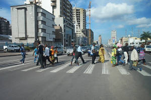 一群行人穿越有車輛和高樓大廈的城市街道。 — 鄉村道路 壁紙
