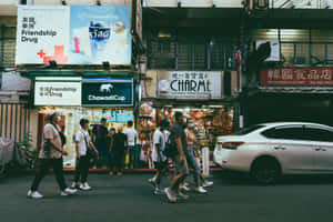 夜晚，行人穿過繁忙的城市街道，閃爍的商店招牌下。 — MacBook Air M2 壁紙