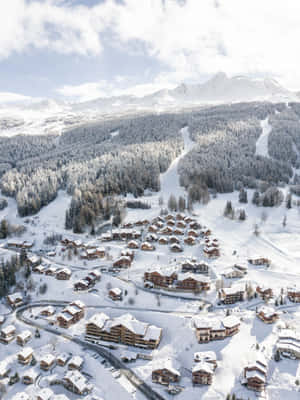 積雪山村，木屋和滑雪道在晴朗天空下。 — iPad Air 13 壁紙
