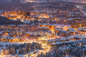 黃昏時分被松樹和蜿蜒道路點亮的雪山小鎮。 — 冬季風景 壁紙