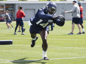 美式足球員在陽光明媚的場地上訓練時接球。 — Dk Metcalf 壁紙