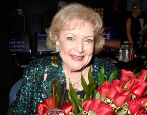 貝蒂·懷特在活動中微笑著手持獎盃和紅玫瑰。