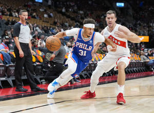 費城76人隊球員在NBA比賽中運球越過多倫多暴龍隊防守球員。 — 費城76人 壁紙