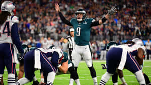 NFL四分衛在球場上高舉雙臂慶祝勝利。 — 超級盃 壁紙