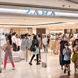佩戴口罩的購物者在Zara店內瀏覽衣架。 — Zara 壁紙