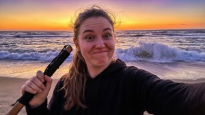 女人在海灘上拿著槳，日落時對著鏡頭微笑 — 最終幻想8 壁紙
