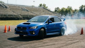 藍色Subaru WRX STI在賽道上漂移，伴有煙霧和橙色錐筒。 — 昴 壁紙