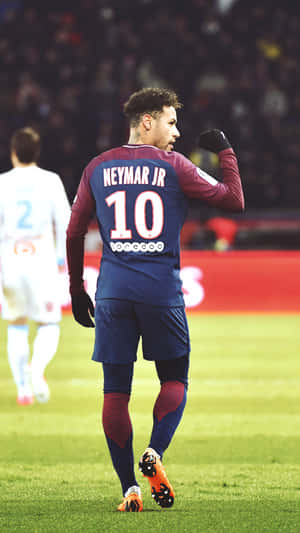 足球員內馬爾（Neymar Jr）在燈光明亮的體育場上身穿藍色和栗色球衣慶祝。 — 酷 壁紙