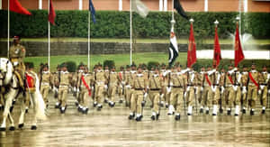 在雨中軍事閱兵中，身穿制服的士兵與旗幟和一名騎兵軍官一起列隊行進。 — 巴基斯坦國旗 壁紙