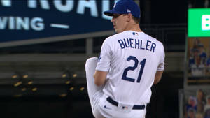 身穿白色21號球衣的棒球投手Buehler在夜間燈光球場上揮臂投球。 — 高對比 壁紙