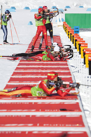 冬季兩項運動員在雪地賽道上進行冬季比賽時射擊步槍。 — 運動 壁紙