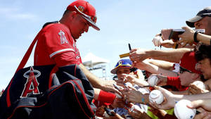 棒球選手為手持棒球的粉絲簽名。 — Mike Trout 壁紙