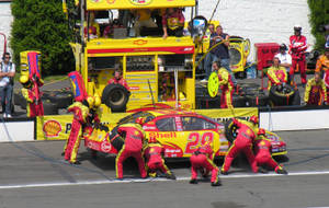 NASCAR維修站團隊在日間賽事中更換賽車輪胎。 — 汽車 4K 壁紙