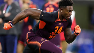 足球運動員在比賽中身穿紫色和橙色制服衝刺。 — Dk Metcalf 壁紙