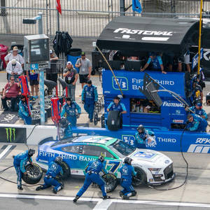 NASCAR維修站團隊在日間比賽中更換賽車輪胎。 — 極限運動 壁紙