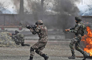 身穿戰鬥裝備的士兵在軍事演習中穿過煙霧和火焰移動。