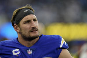 NFL四分衛身穿帶有隊長標誌的藍色球衣，在比賽中顯得專注。 — 運動 壁紙