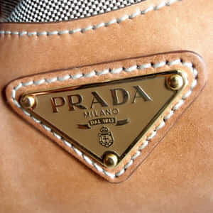 淺棕色皮革Prada手提包，帶有金色標誌牌和白色縫線。 — Prada 壁紙