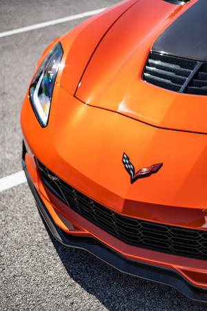 瀝青路上帶有黑色點綴的橙色Corvette跑車前引擎蓋。 — Vans 標誌 壁紙