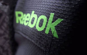 近距離拍攝黑色運動布料上的Reebok標誌。 — 銳步 壁紙
