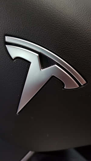 黑色皮革汽車內飾上的時尚銀色 Tesla 標誌。 — 特斯拉 壁紙