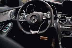 近距離拍攝 Mercedes-AMG 汽車內部，黑色方向盤和碳纖維飾邊。 — Mercedes Benz C300 壁紙