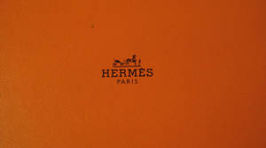 橙色皮革配 Hermès Paris 標誌和馬車徽章。 — 淺棕色美學動圖 壁紙